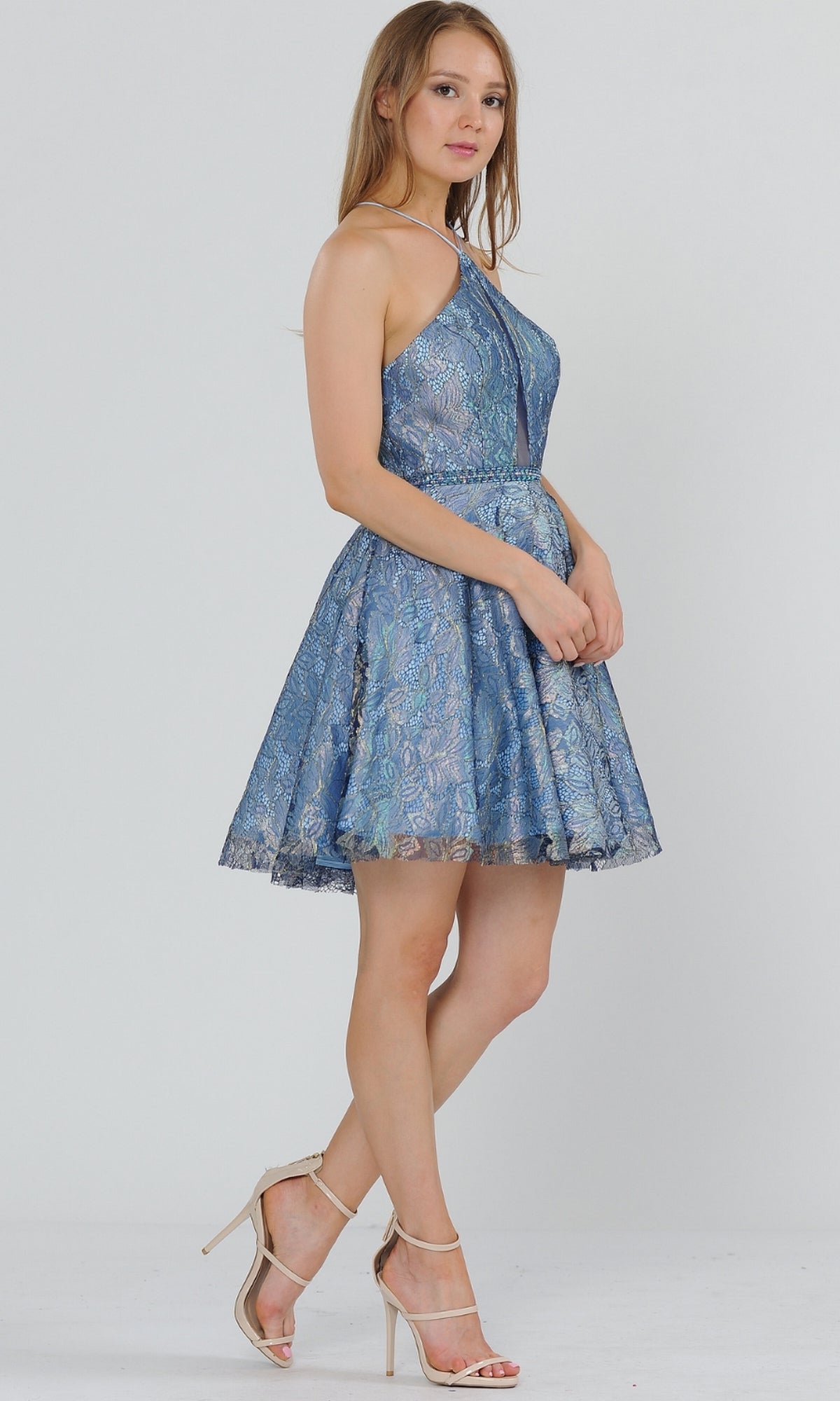 A woman wears the Glitter-Mesh Short A-Line Homecoming Dress 8506 with a flared skirt and beige high-heeled sandals, standing against a plain light background.